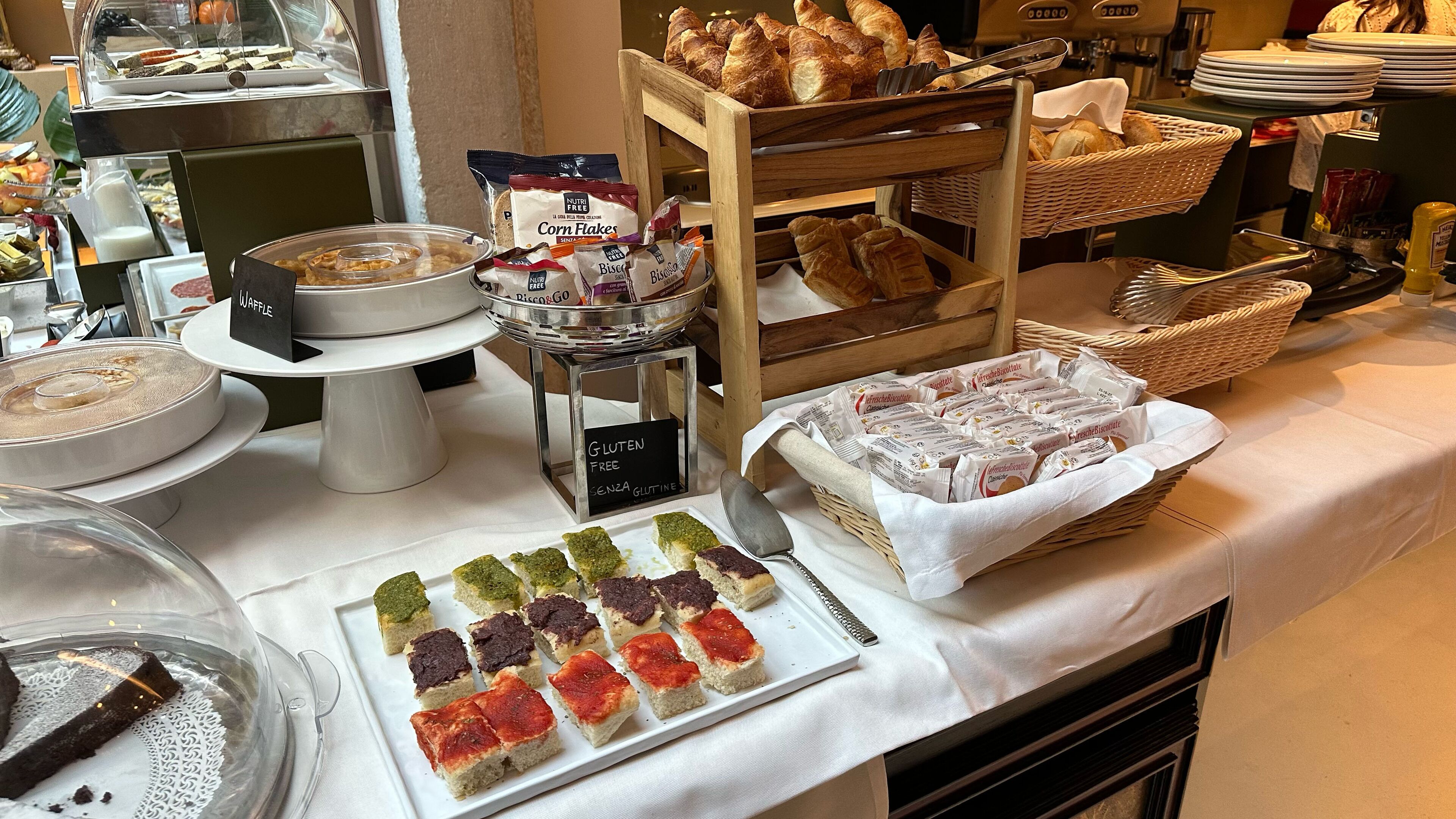 A buffet with various food items including waffles, pastries, and gluten-free options.