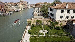 Un río con barcos, un jardín cuidado y edificios históricos a lo largo de la orilla.