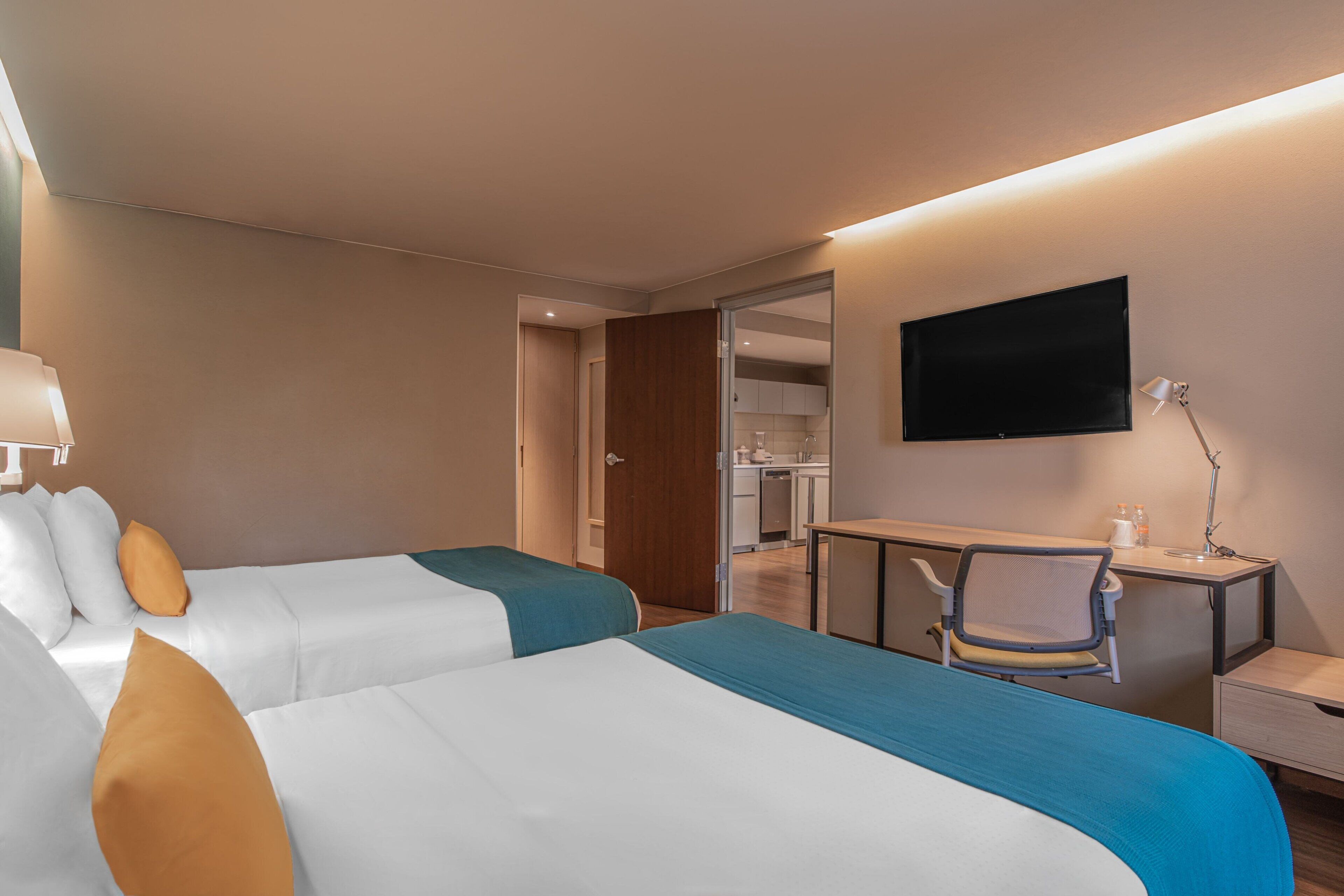 Una habitación de hotel con dos camas, un escritorio, una silla, un televisor y un armario.