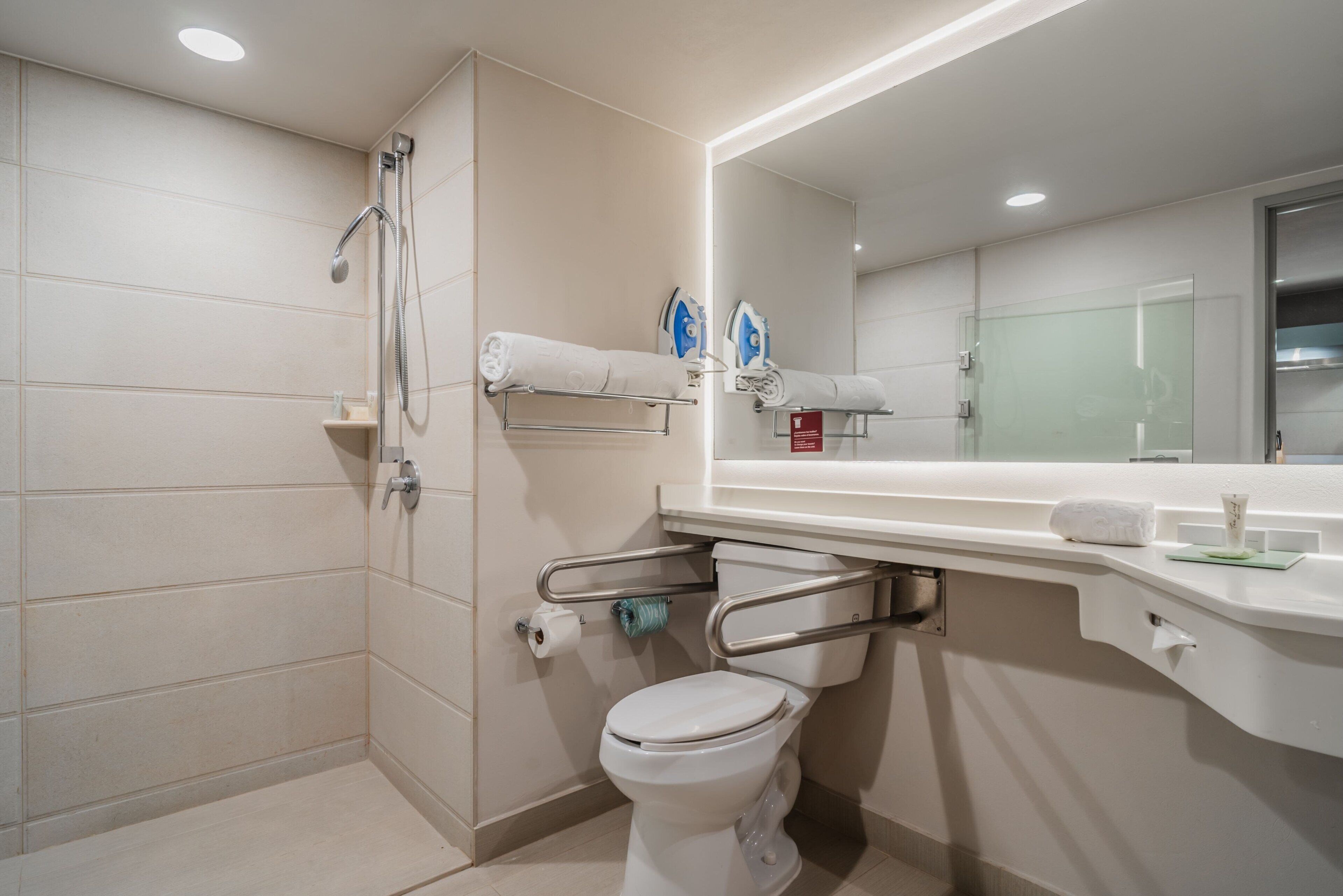 Une salle de bain moderne équipée d’une douche, de toilettes et d’un grand miroir.