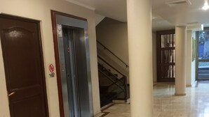 A corridor with a marble floor, a door, an elevator, and a staircase. - Hotel Alcala del Rio (Santiago)