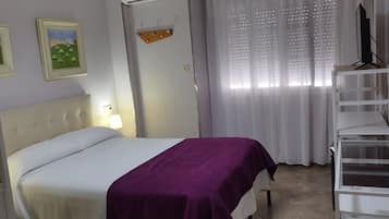 Quarto com cama, televisão em suporte, escada e janela com cortinas.