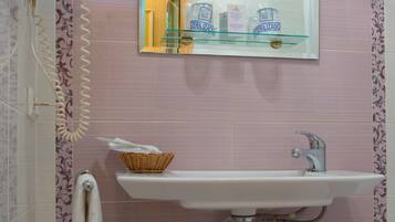 A bathroom with a white sink, a mirror, a telephone, and a basket on the wall.