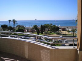 Un balcón con vista a la playa y un estacionamiento.