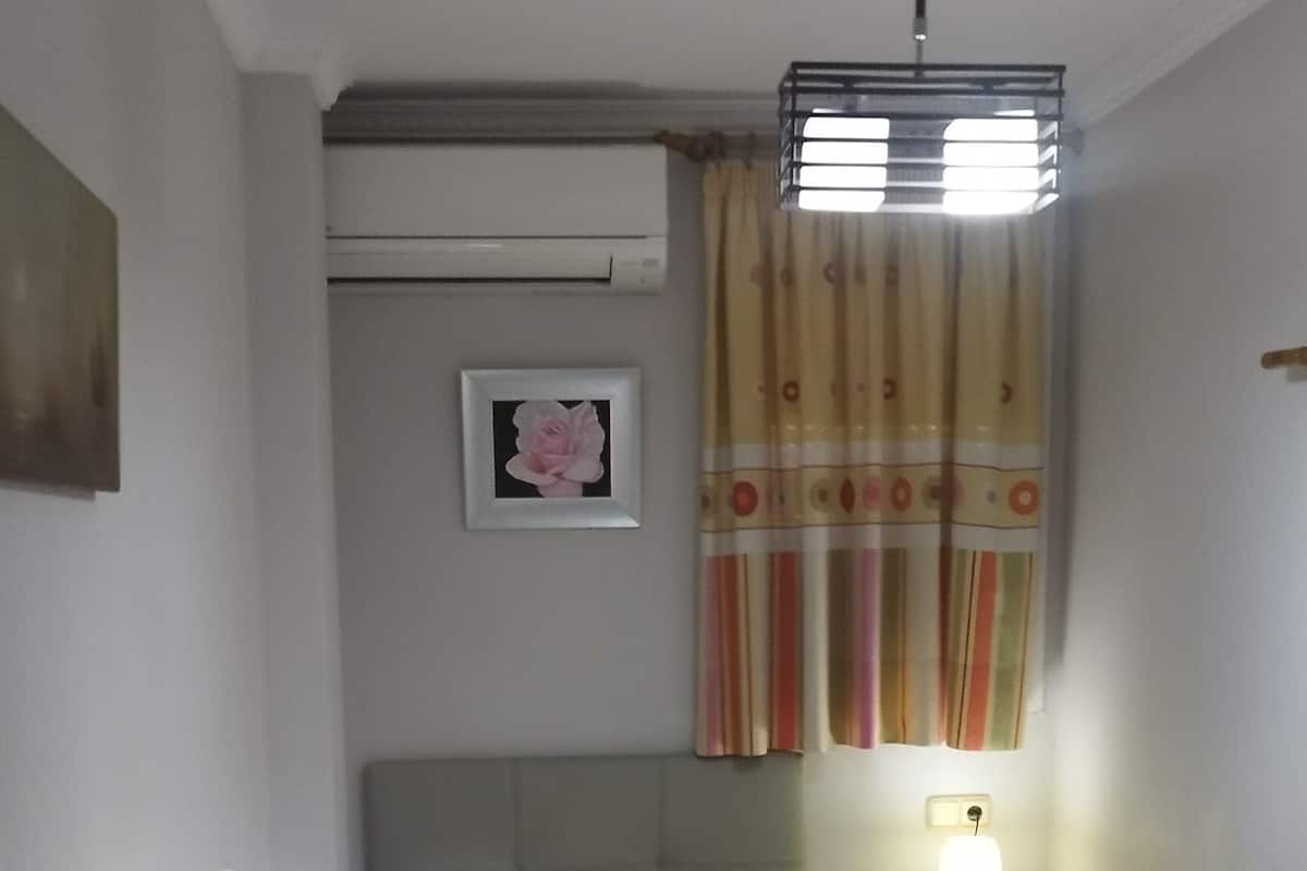 Une petite chambre à coucher, bien rangée, avec un lit, une table de chevet et un bureau avec une chaise.
