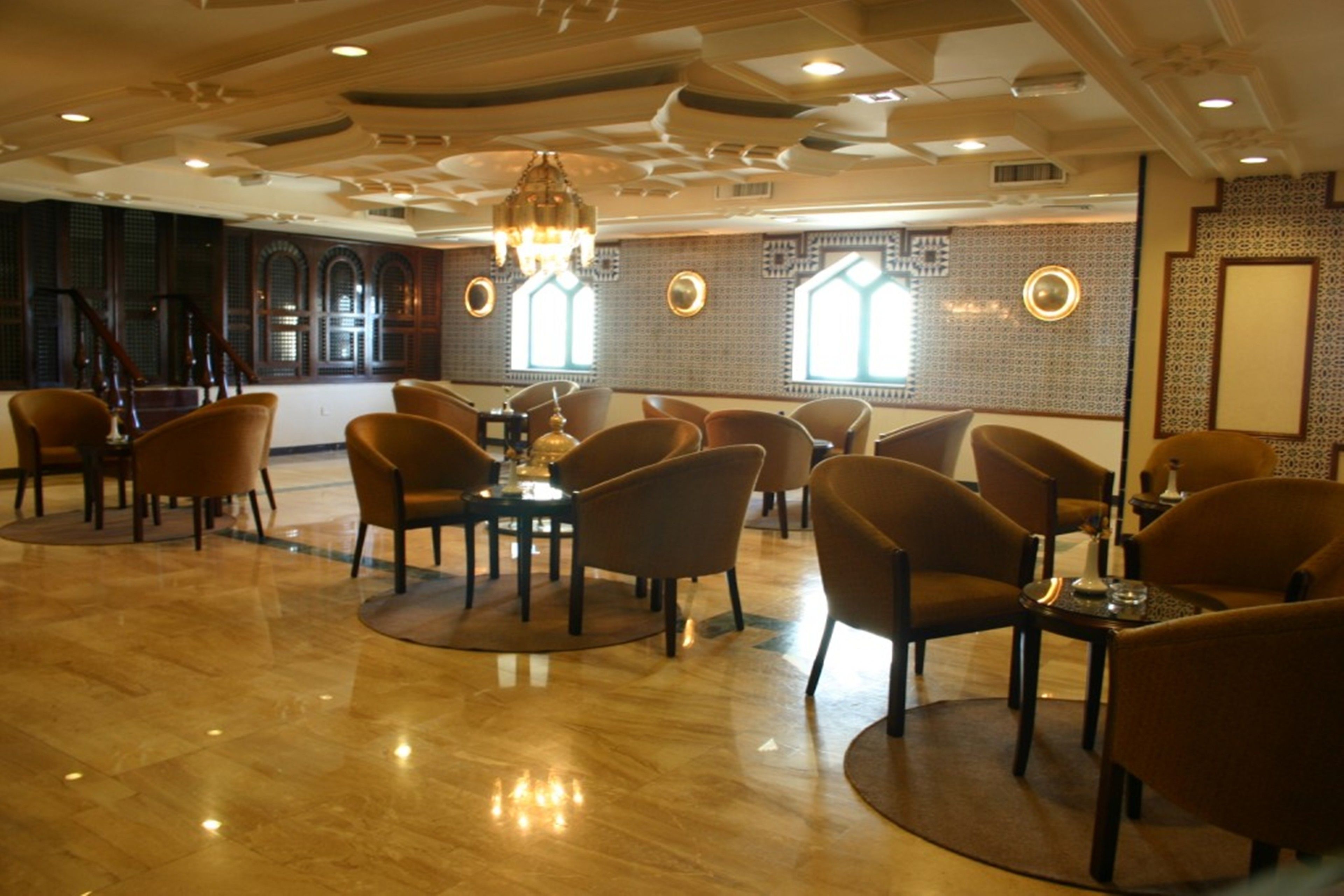 A spacious hotel lobby with a polished marble floor, comfortable seating areas, and large windows allowing natural light.
