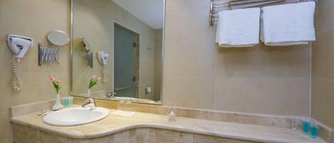 A bathroom with a sink, mirror, towel rack, and toiletries.