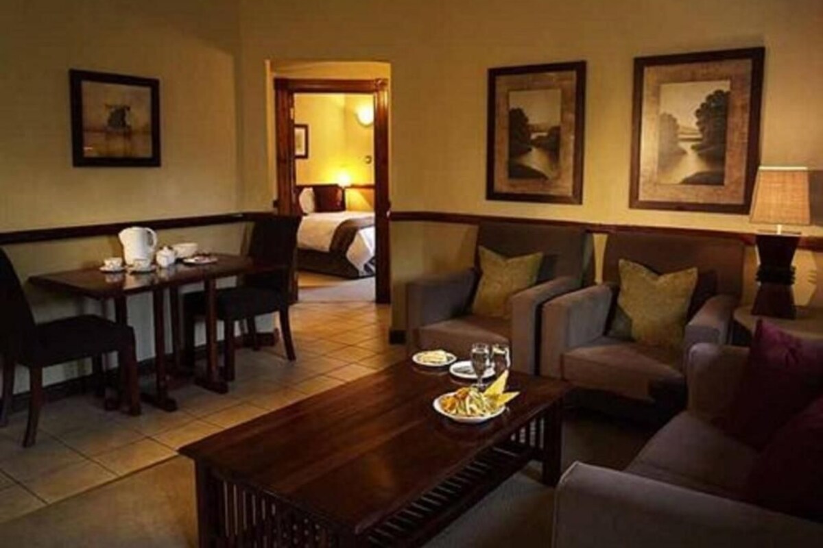 A hotel room with a dining area, a sofa, and a bed.