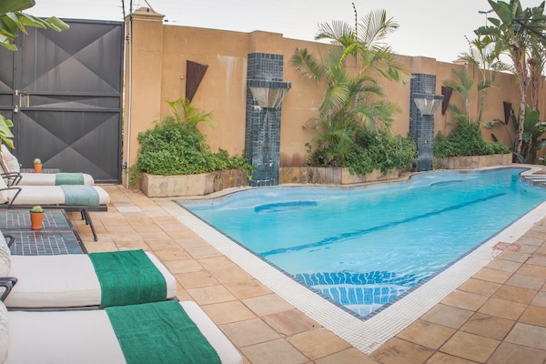 Una piscina al aire libre, sillones reclinables de piscina