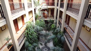 Un atrium à plusieurs niveaux, doté d’une cour centrale avec un sol carrelé et des plantes en pot.