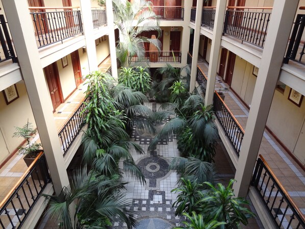 A multi-level atrium with a central courtyard featuring tiled flooring and potted plants.