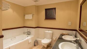 A bathroom with a bathtub, toilet, and two sinks.