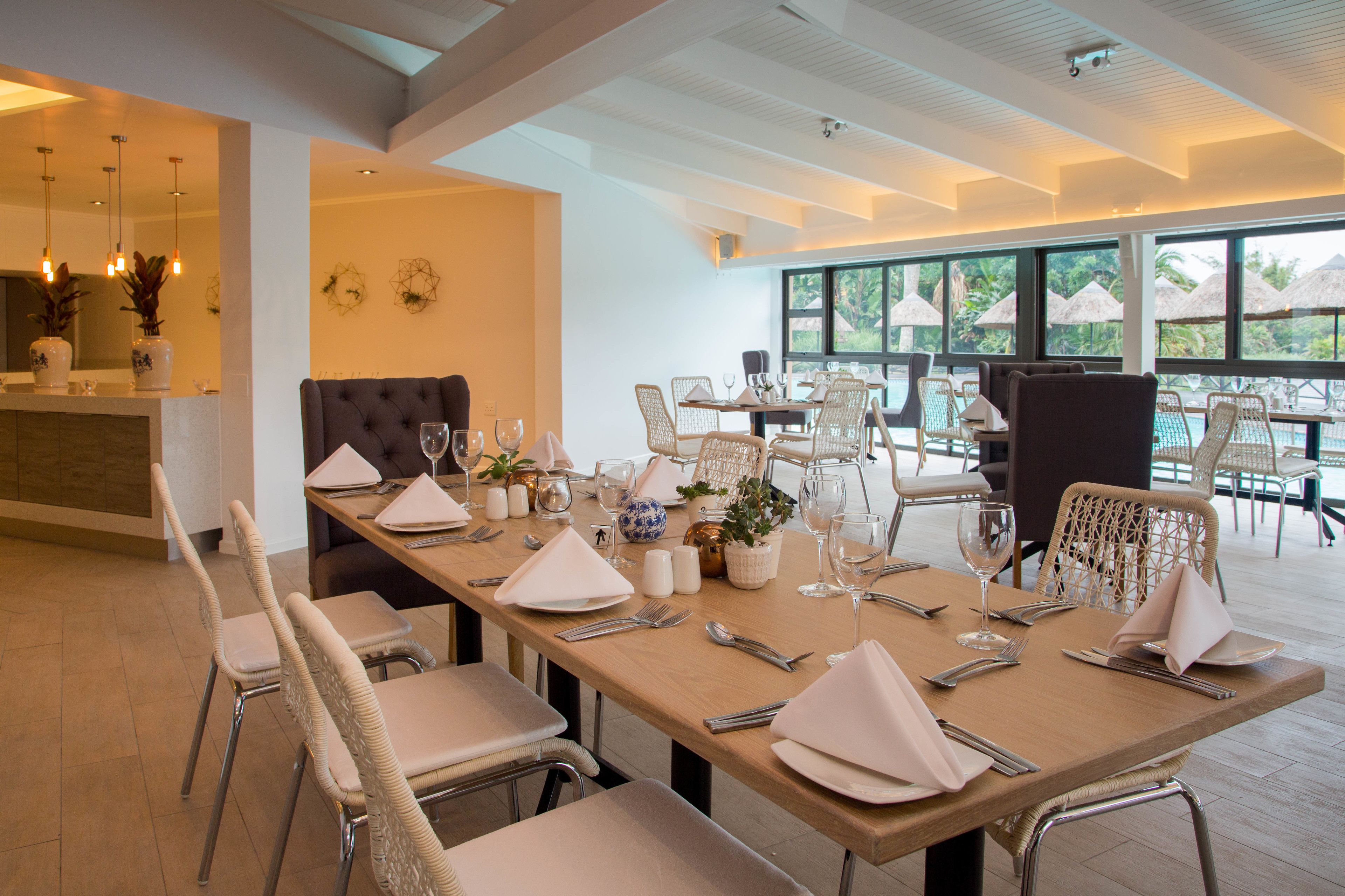 Un espace repas avec une longue table dressée pour le repas, entourée de chaises en osier.
