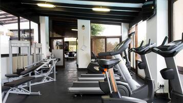 Un gimnasio con cintas de correr, máquinas de pesas y un espejo grande.