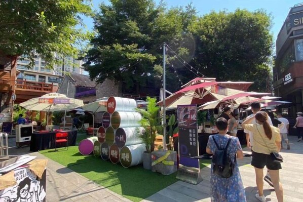 A street market with food stalls and a green artificial turf area.