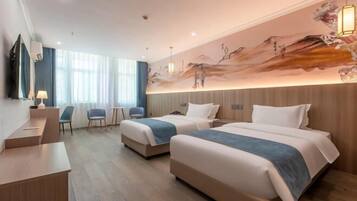 Habitación de hotel con dos camas, un escritorio, sillas y un mural grande en la pared.
