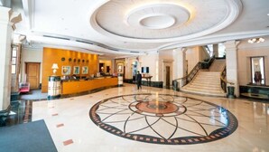 A spacious lobby with a central circular floor design, a reception desk, and a staircase leading to upper floors. - Carrianna Hotel (Foshan)
