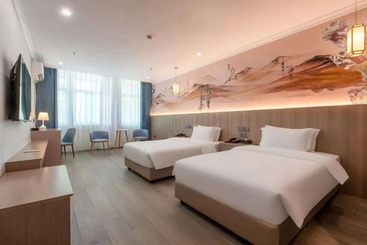 A hotel room with two beds, a desk, and a chair.