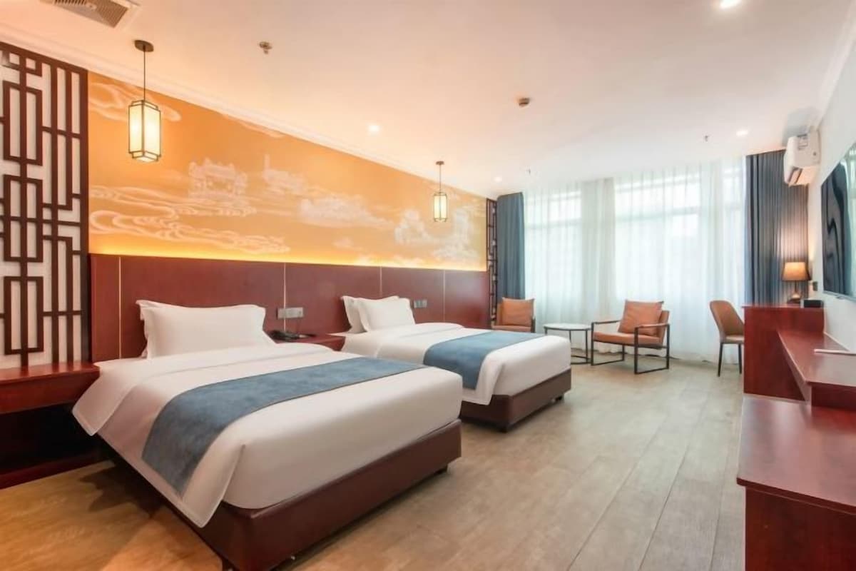 A hotel room with two beds, a desk, and a chair.