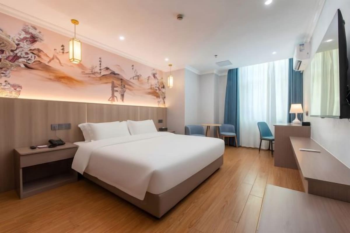 A hotel room with a large bed, bedside tables, a desk, and a chair.