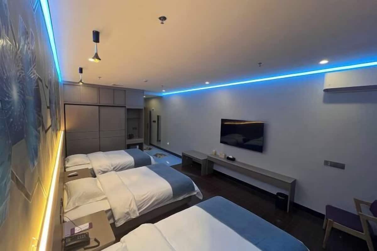 A modern hotel room with two beds, a TV, a desk, and a bench.