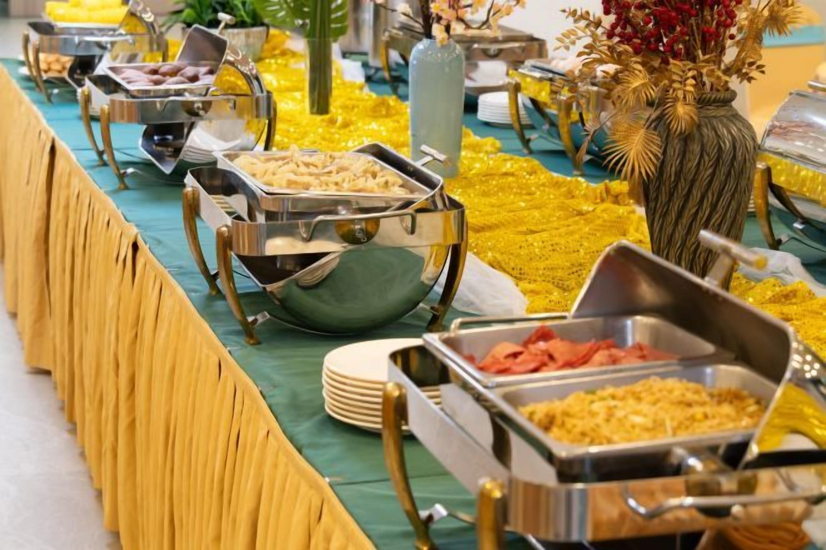 Montaje de buffet con diversos alimentos en recipientes metálicos.