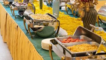Montaje de buffet con diversos alimentos en recipientes metálicos.