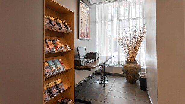 A modern office space with a desk, computer, and shelves with books.