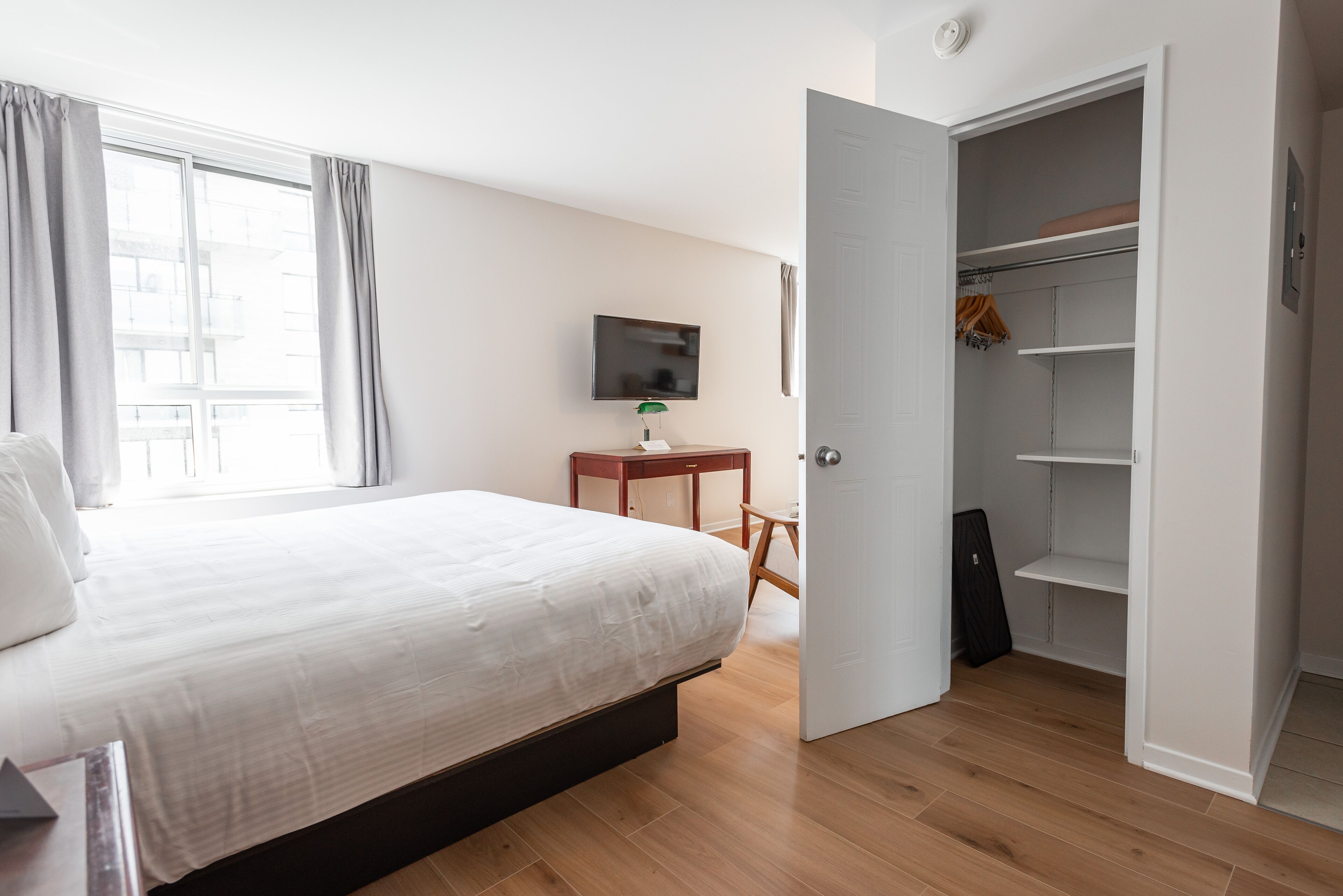 Un dormitorio con cama, televisión, escritorio y armario.