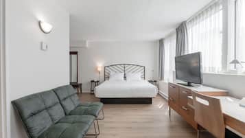 Ein Hotelzimmer mit Bett, Fernseher, Schreibtisch und einer Couch.