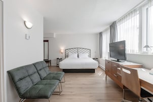 A hotel room with a bed, a TV, a desk, and a couch.