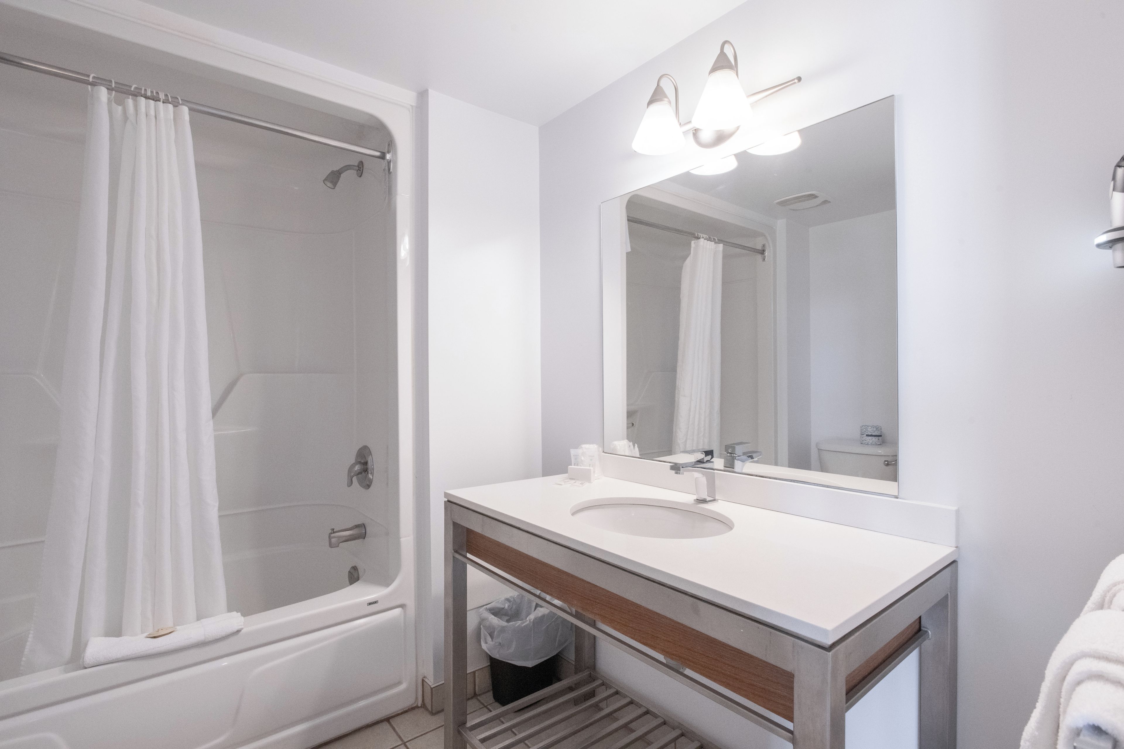 A modern bathroom with a shower, a sink, and a mirror.