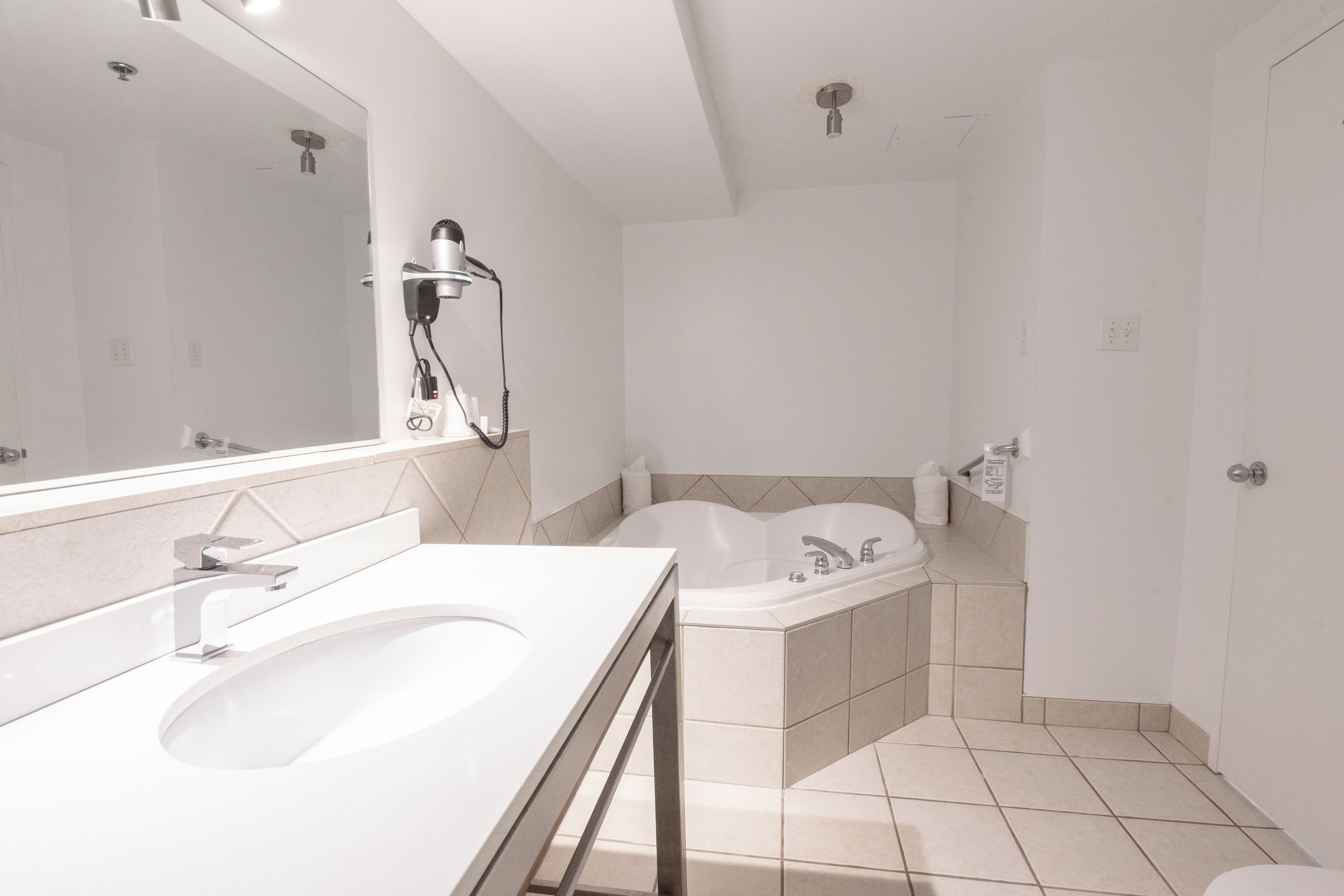 A modern bathroom with a large sink, a mirror, a shower, and a bathtub.