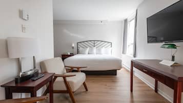Habitación de hotel con cama, escritorio, silla, televisor y lámpara.