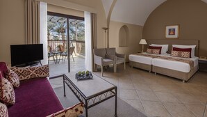 A hotel room with a balcony, a TV, a sofa, a bed, and a dining area. - JAZ Makadi Saraya Resort - All inclusive (Makadi Bay)