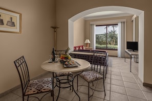 A dining area with a round table, chairs, and a view of the outdoors through a window. - JAZ Makadi Saraya Resort - All inclusive (Makadi Bay)