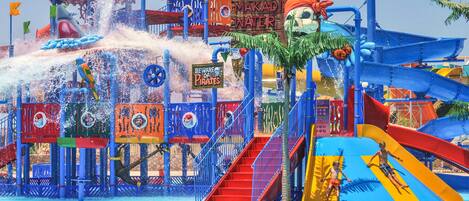 A water park with slides, a pirate-themed structure, and a sign warning of pirates.