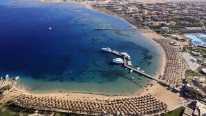 An aerial view of a coastal resort with a marina, beach, and resort buildings. - JAZ Makadi Saraya Resort - All inclusive (Makadi Bay)