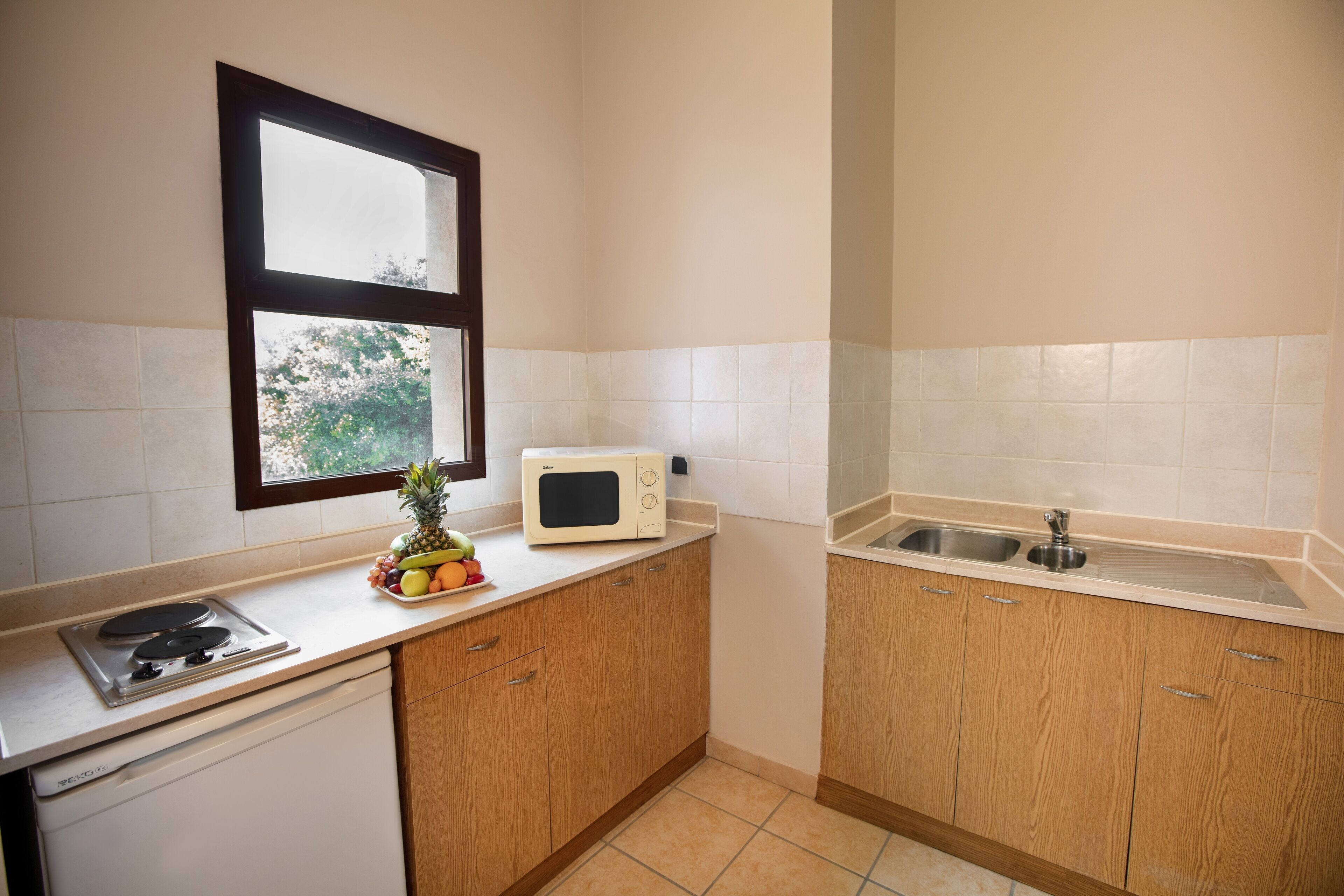A compact kitchen with a microwave, sink, and wooden cabinets.