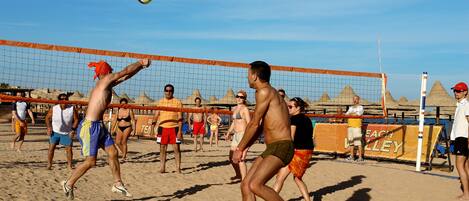 Un partido de voleibol de playa con jugadores con distintos trajes de baño y una red en el centro.