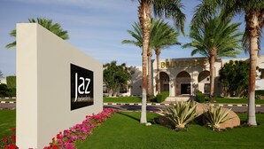 Un letrero con 'jaz belvedere' y un edificio con arcos y palmeras.