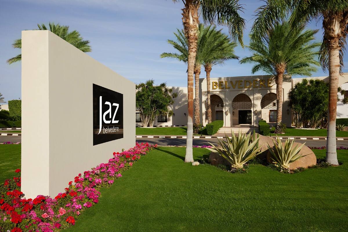 A sign with 'jaz belvedere' and a building with arches and palm trees.