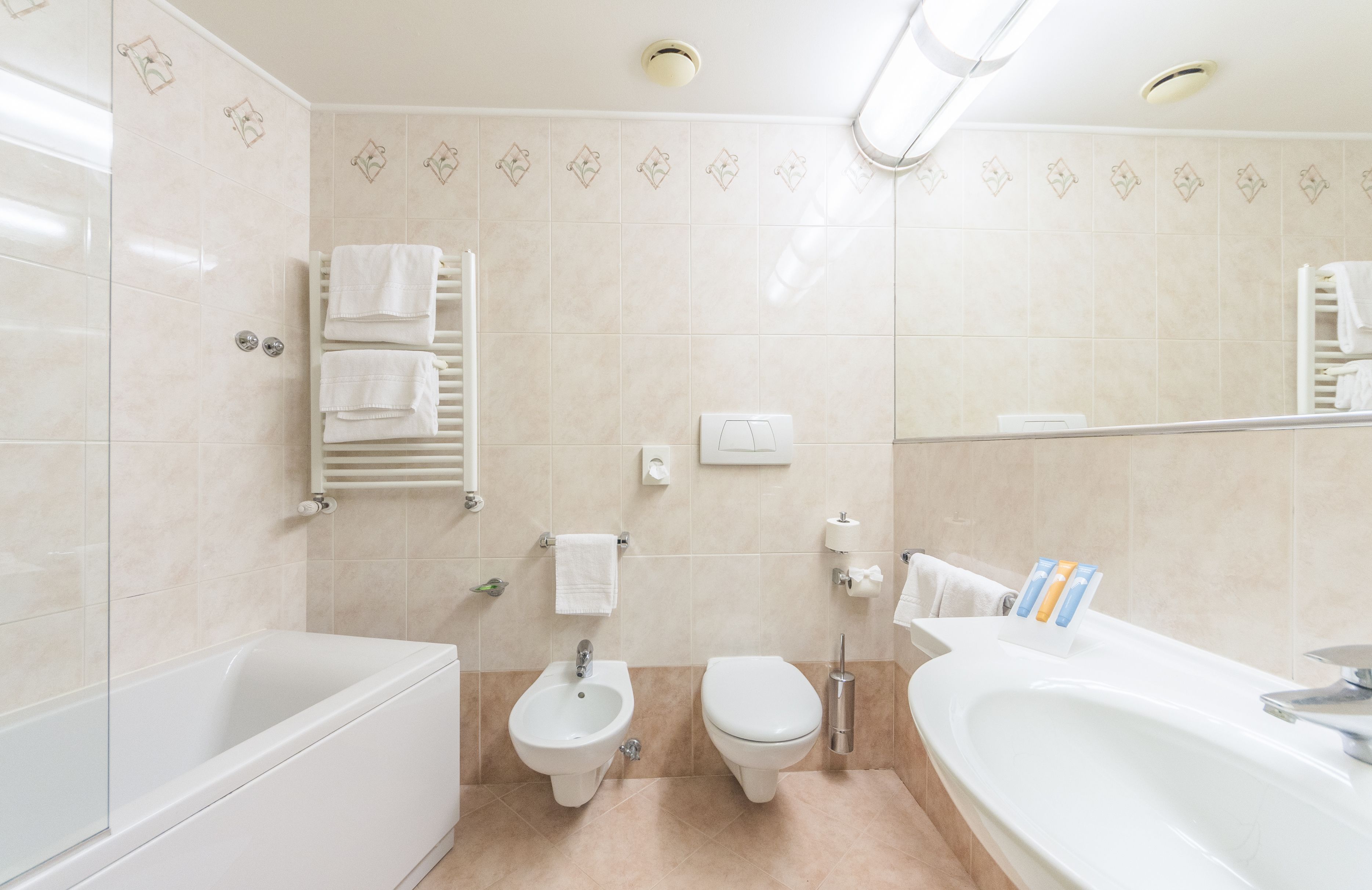 A modern bathroom with a bathtub, two toilets, a bidet, and a sink.