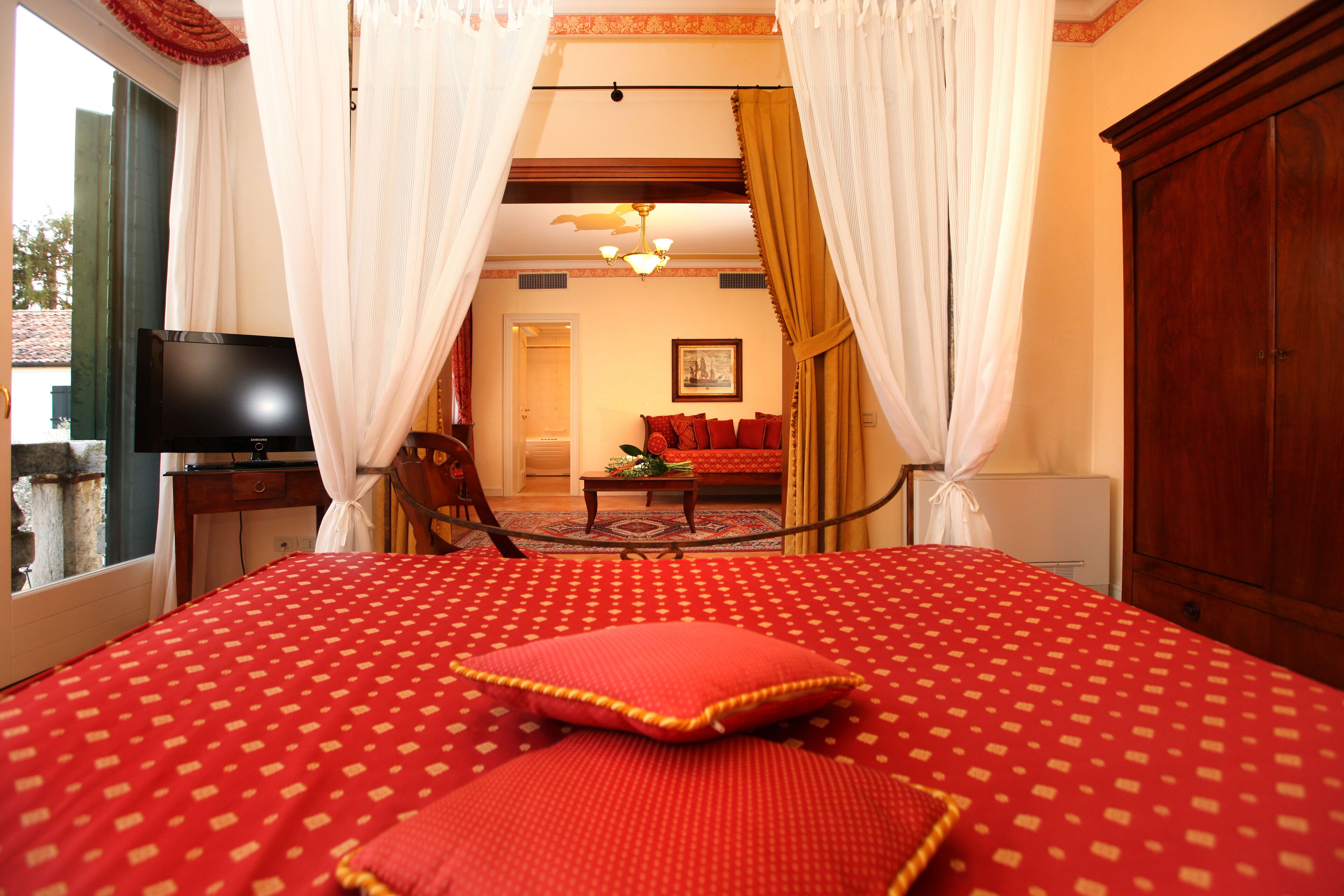 A hotel room with a large bed, a television, and a wardrobe.
