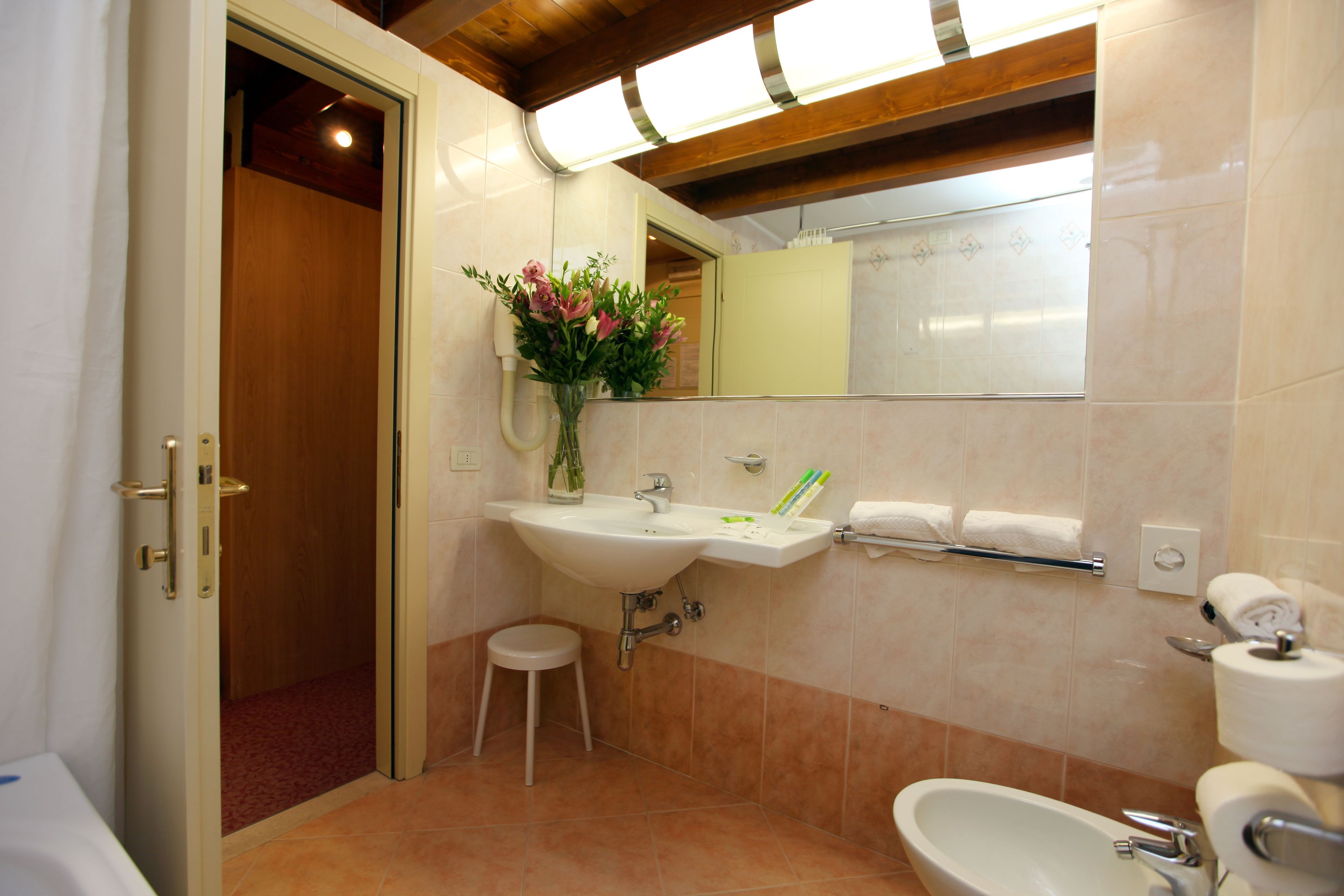 A bathroom with a sink, mirror, toilet, and a small stool.