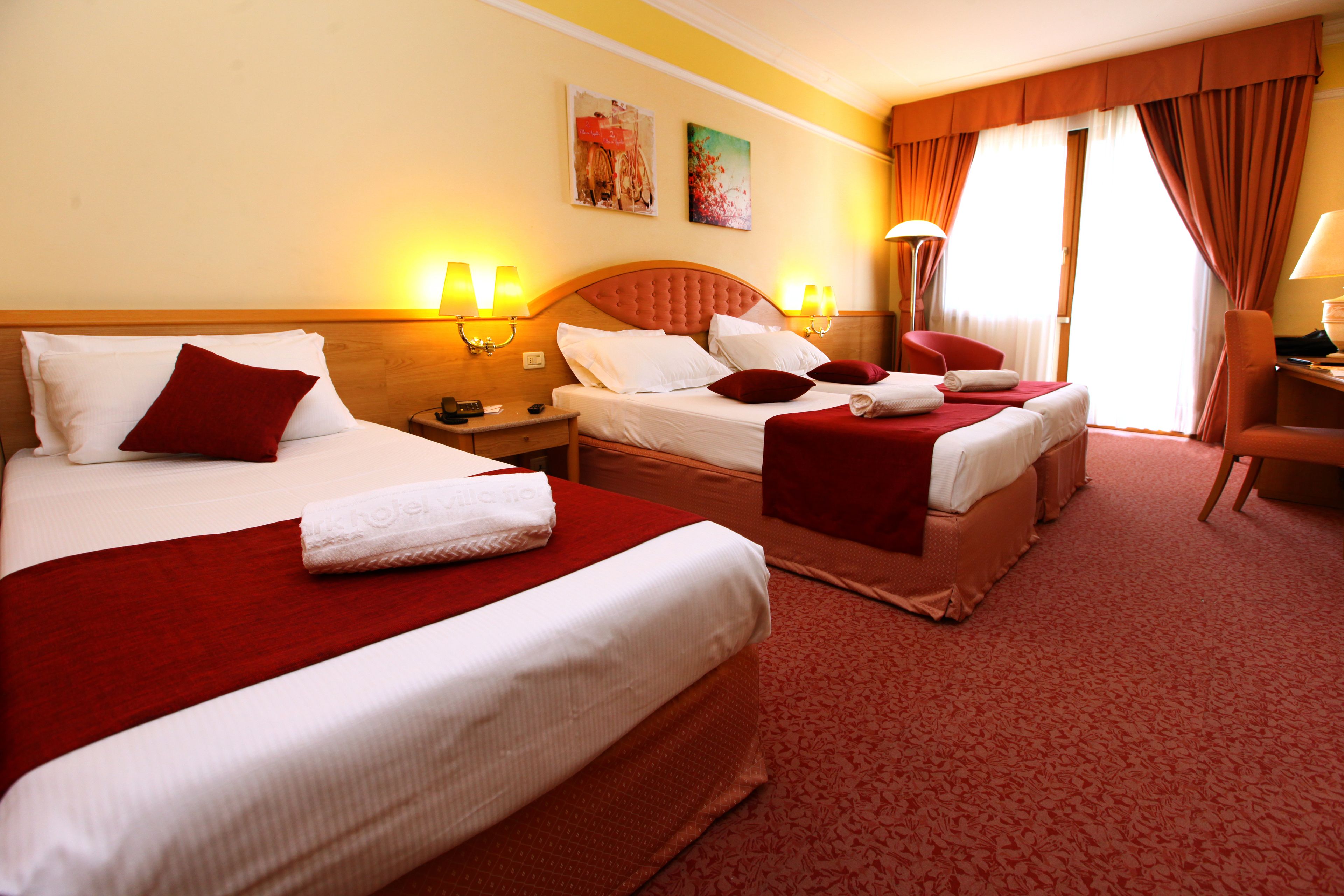 Habitación de hotel con dos camas, un área de estar y vistas al exterior.