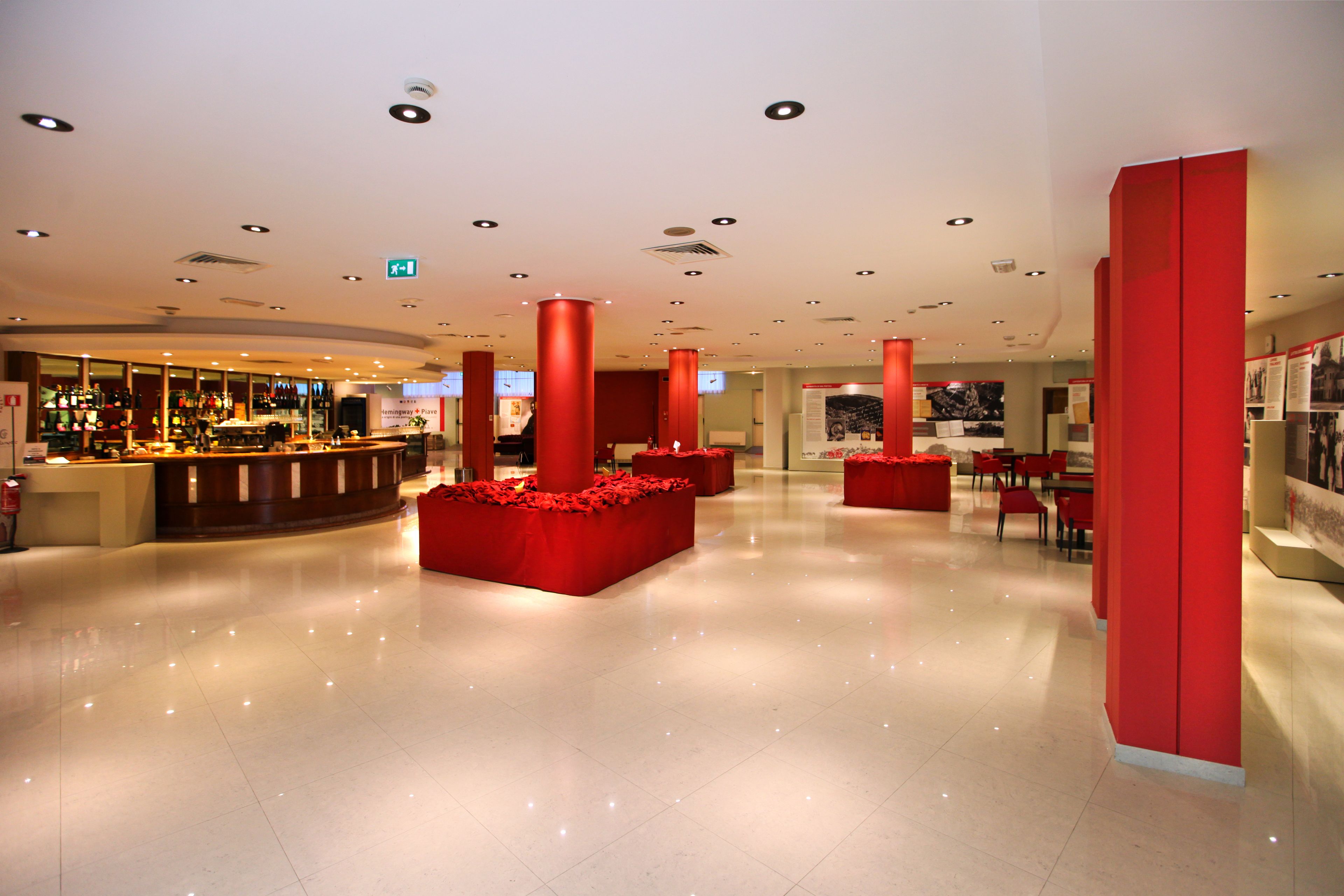 Un hall d’entrée spacieux avec un bar, des sièges rouges et un design épuré et moderne.