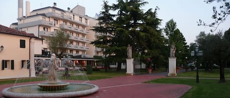 Un patio con una fuente, una estatua y un edificio con balcones.
