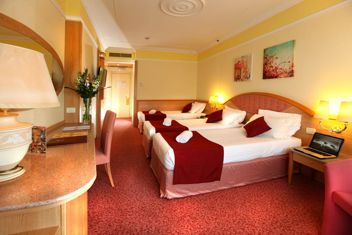 Une chambre d’hôtel avec deux lits, un bureau avec un ordinateur portable, une chaise et un miroir.