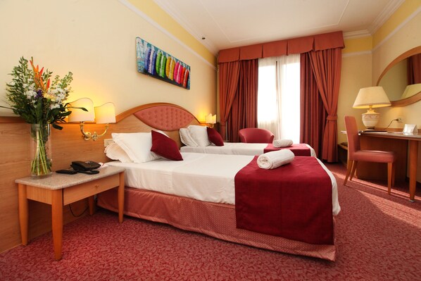 A hotel room with two beds, a desk, a chair, a lamp, and a painting on the wall. - Park Hotel Villa Fiorita (Monastier di Treviso)